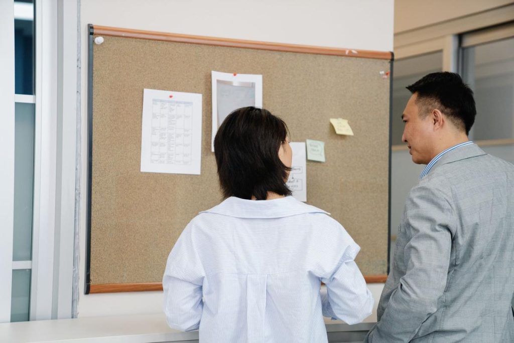 Deux individus consultent des informations sur un panneau d'affichage dans un cadre professionnel