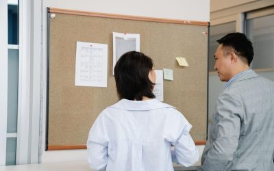 Deux individus consultent des informations sur un panneau d'affichage dans un cadre professionnel