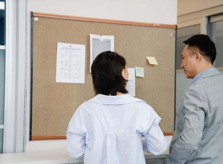 Deux individus consultent des informations sur un panneau d'affichage dans un cadre professionnel