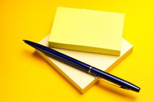 Carnet et stylo bleu sur fond jaune