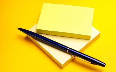 Carnet et stylo bleu sur fond jaune
