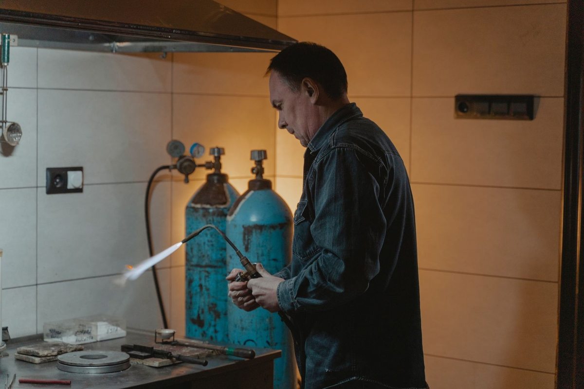 Homme manipulant flamme de soudure près de deux bouteilles de gaz Homme manipulant flamme de soudure près de deux bouteilles de gaz