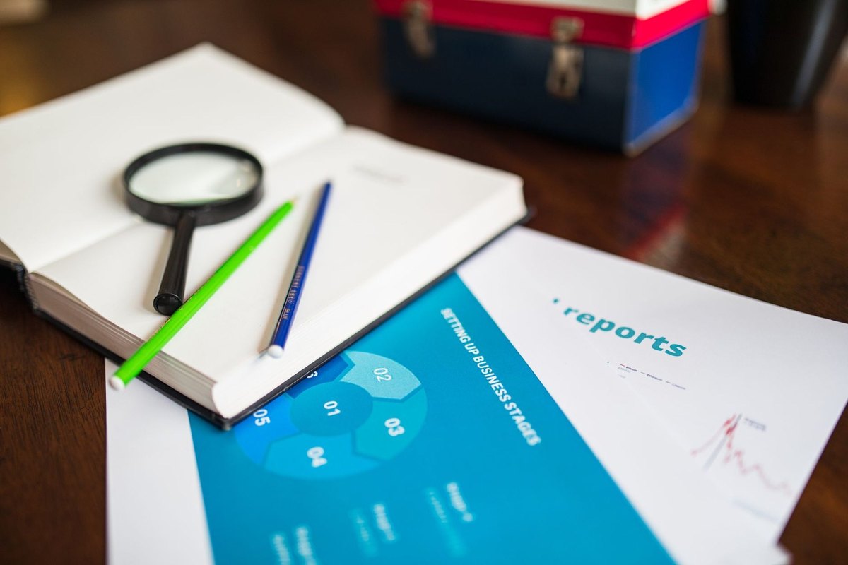 Carnet ouvert avec stylo et crayon, loupe, documents et rapport sur une table Carnet ouvert avec stylo et crayon, loupe, documents et rapport sur une table