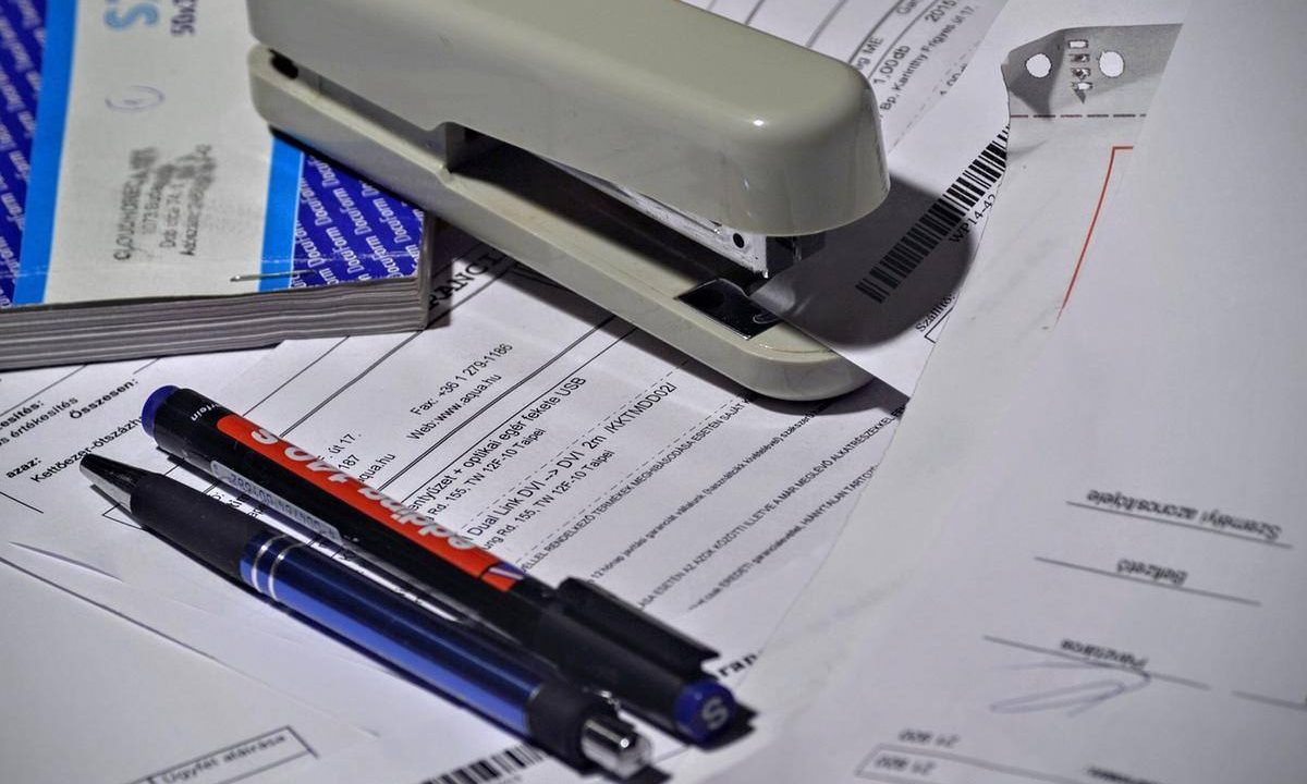 Stylos sur documents avec agrafeuse et classeur sur bureau