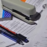 Stylos sur documents avec agrafeuse et classeur sur bureau