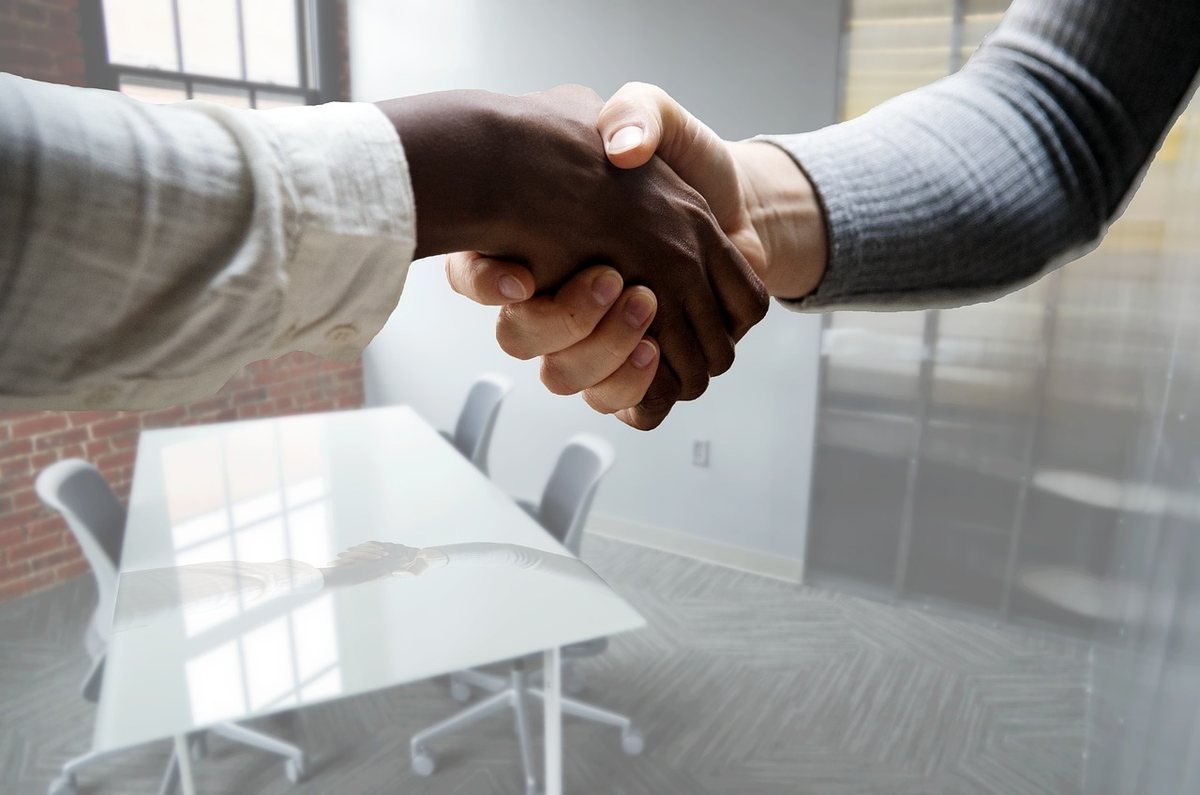 Deux personnes en tenue professionnelle se serrent la main dans un bureau moderne
