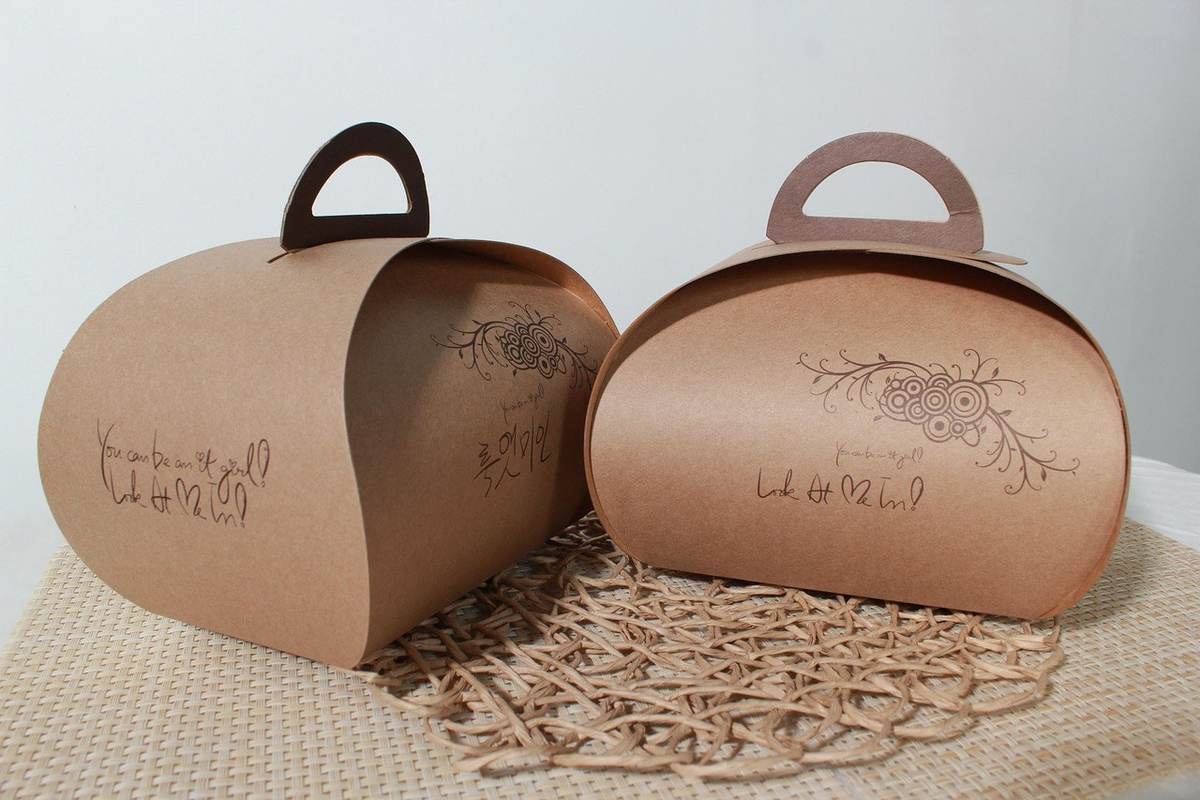 Boîtes en carton brun avec motifs et poignées sur une surface texturée