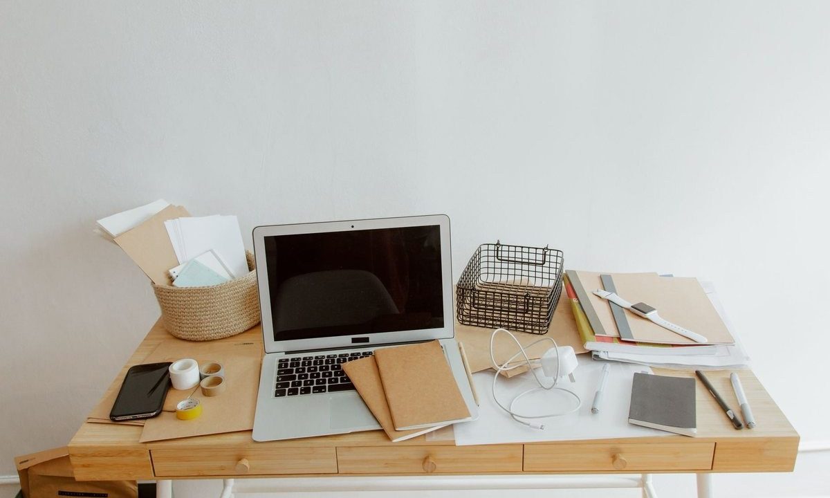 Bureau blanc avec ordinateur portable, documents, téléphone et fournitures disposés organisés
