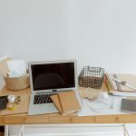 Bureau blanc avec ordinateur portable, documents, téléphone et fournitures disposés organisés