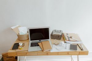Bureau blanc avec ordinateur portable, documents, téléphone et fournitures disposés organisés