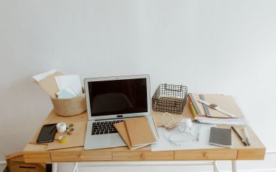 Bureau blanc avec ordinateur portable, documents, téléphone et fournitures disposés organisés