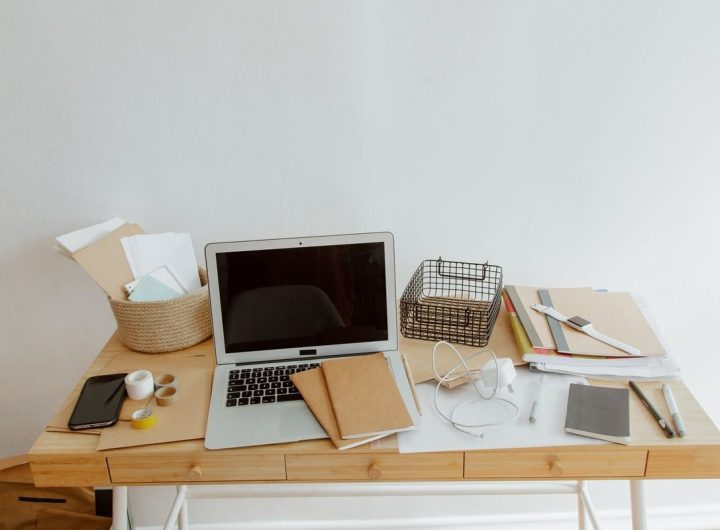 Bureau blanc avec ordinateur portable, documents, téléphone et fournitures disposés organisés