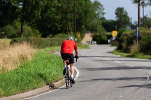 Cycliste sur route, casque, gants, arbres, buissons, panneau signalétique