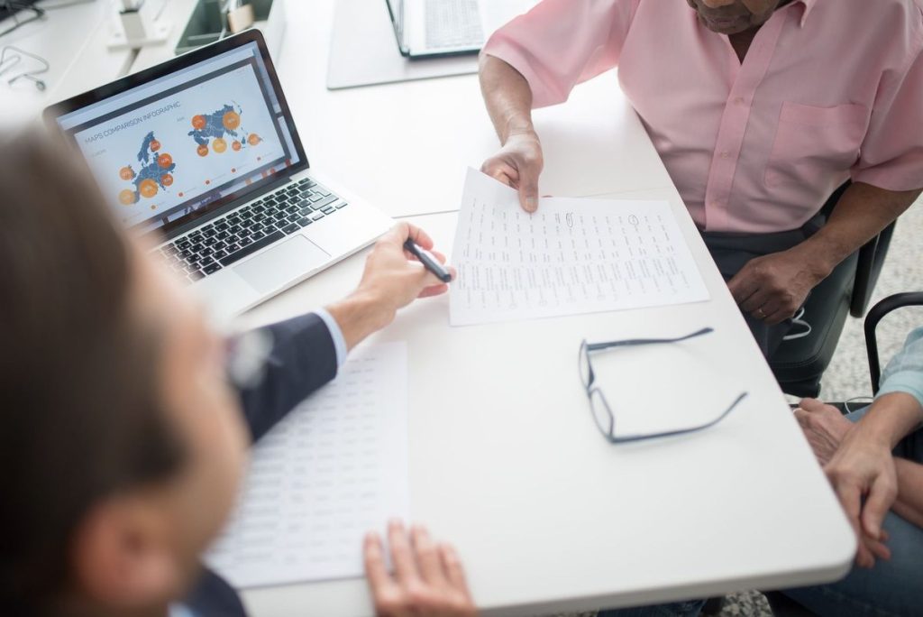 Trois personnes discutent autour d'un ordinateur portable et de documents sur une table