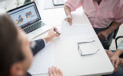 Trois personnes discutent autour d'un ordinateur portable et de documents sur une table