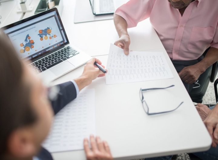 Trois personnes discutent autour d'un ordinateur portable et de documents sur une table