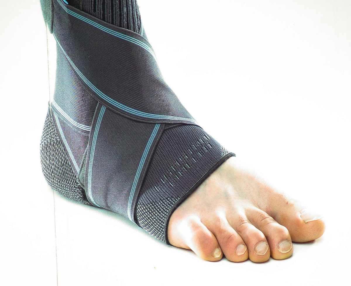 Pied humain avec un dispositif de soutien gris et bleu, sur une surface blanche Pied humain avec un dispositif de soutien gris et bleu, sur une surface blanche