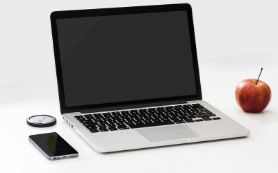 Laptop ouvert, smartphone, pomme et disque dur sur une table blanche