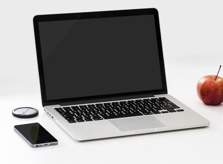 Laptop ouvert, smartphone, pomme et disque dur sur une table blanche