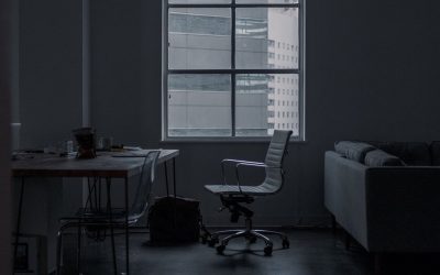 Salle sombre avec bureau, chaise, canapé, fenêtre et sac