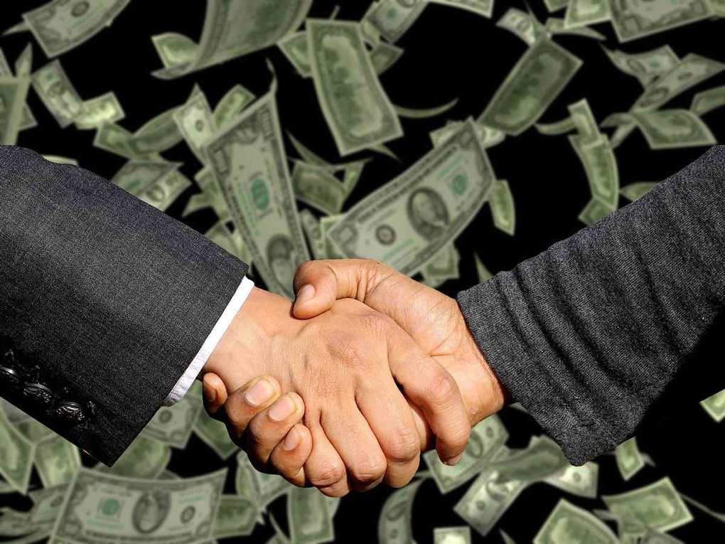 Homme et femme serrant la main au milieu de billets de dollar en suspension Homme et femme serrant la main au milieu de billets de dollar en suspension