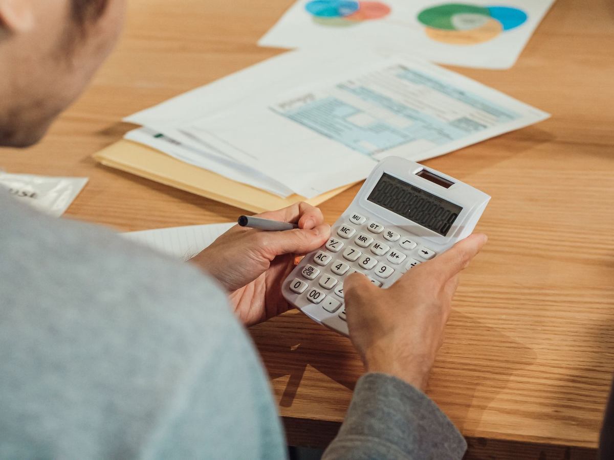 Homme utilisant une calculatrice et un stylo sur un bureau avec des documents Homme utilisant une calculatrice et un stylo sur un bureau avec des documents