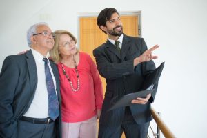 Homme en costume pointant un document, deux personnes observant, dans un bureau