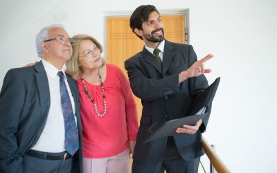 Homme en costume pointant un document, deux personnes observant, dans un bureau