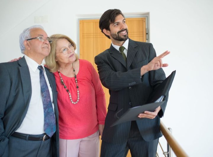 Homme en costume pointant un document, deux personnes observant, dans un bureau