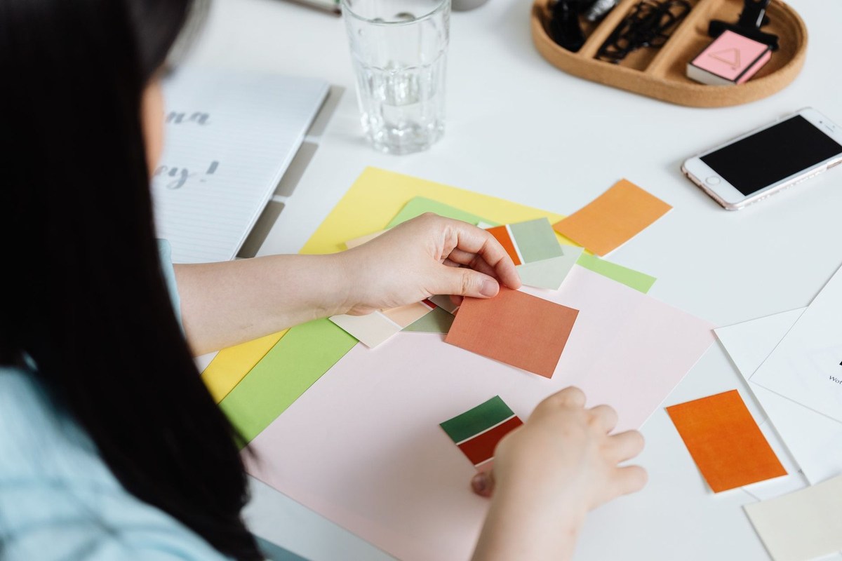 Une personne organise des papiers colorés sur une table blanche avec des fournitures artistiques