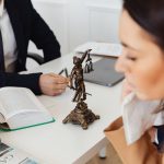 Homme et femme en conversation dans un bureau avec des documents et une statue de justice