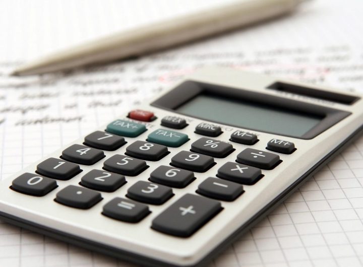 Calculatrice et stylo posés sur des documents comptables manuscrits