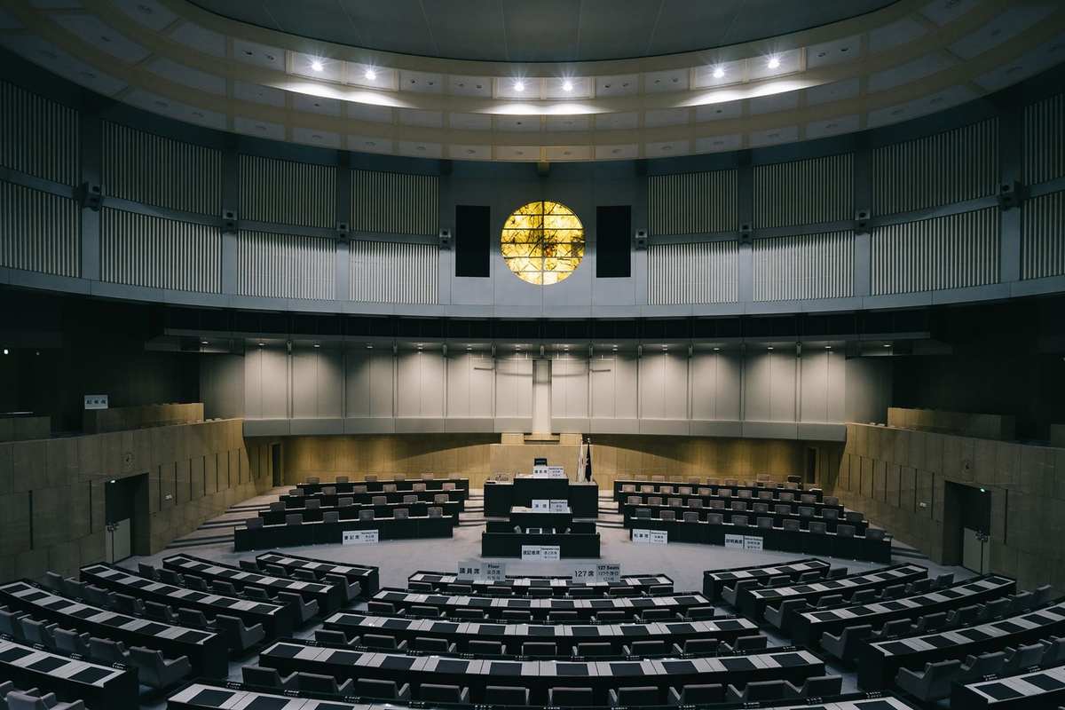 Salle de conférence avec amphithéâtre, chaises, tables, podium, lumière, mur courbe