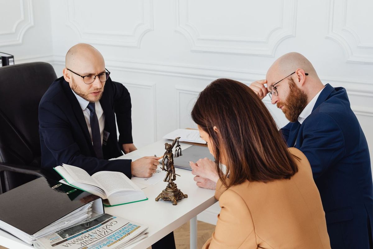 Professionnels discutant autour d'une table avec des documents et une statue de justice