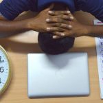 Homme endormi devant ordinateur, montre d'horloge, agenda sur bureau en bois