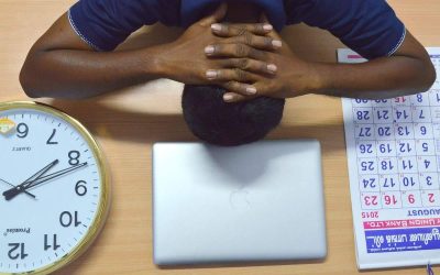 Homme endormi devant ordinateur, montre d'horloge, agenda sur bureau en bois