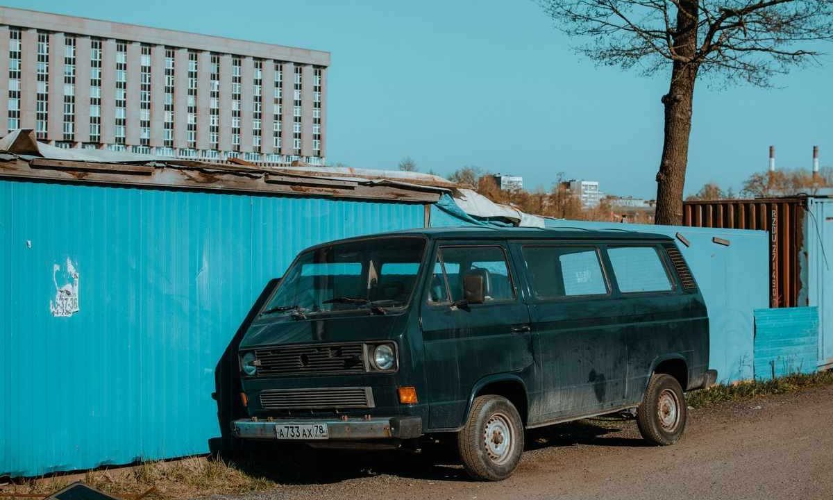 Van noir à côté d'un conteneur bleu sous un ciel clair