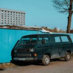 Van noir à côté d'un conteneur bleu sous un ciel clair