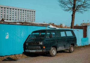 Van noir à côté d'un conteneur bleu sous un ciel clair