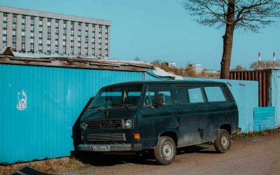 Van noir à côté d'un conteneur bleu sous un ciel clair