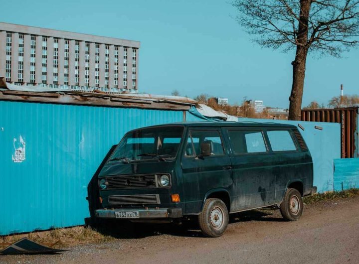 Van noir à côté d'un conteneur bleu sous un ciel clair